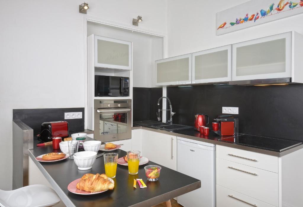 une cuisine avec des placards blancs et une table avec de la nourriture. dans l'établissement Hyper Centre Place Imbach, à Angers