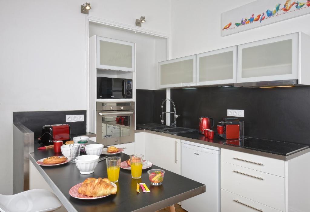 a kitchen with white cabinets and a table with food on it at Hyper Centre Place Imbach in Angers
