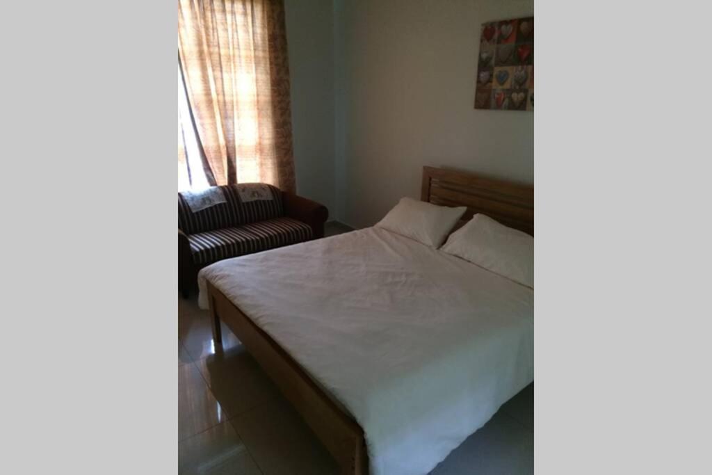 um quarto com uma cama, uma cadeira e uma janela em Homestay Ayi em Ayer Keroh