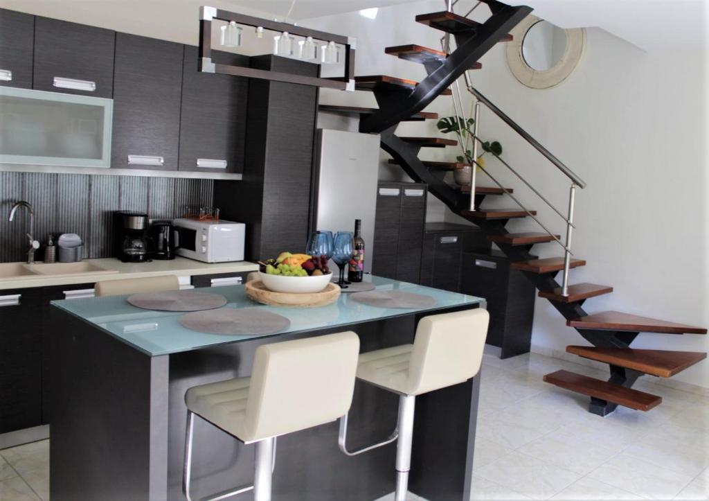 a kitchen with a island with chairs and a staircase at Casa Ariadne in Plataniás