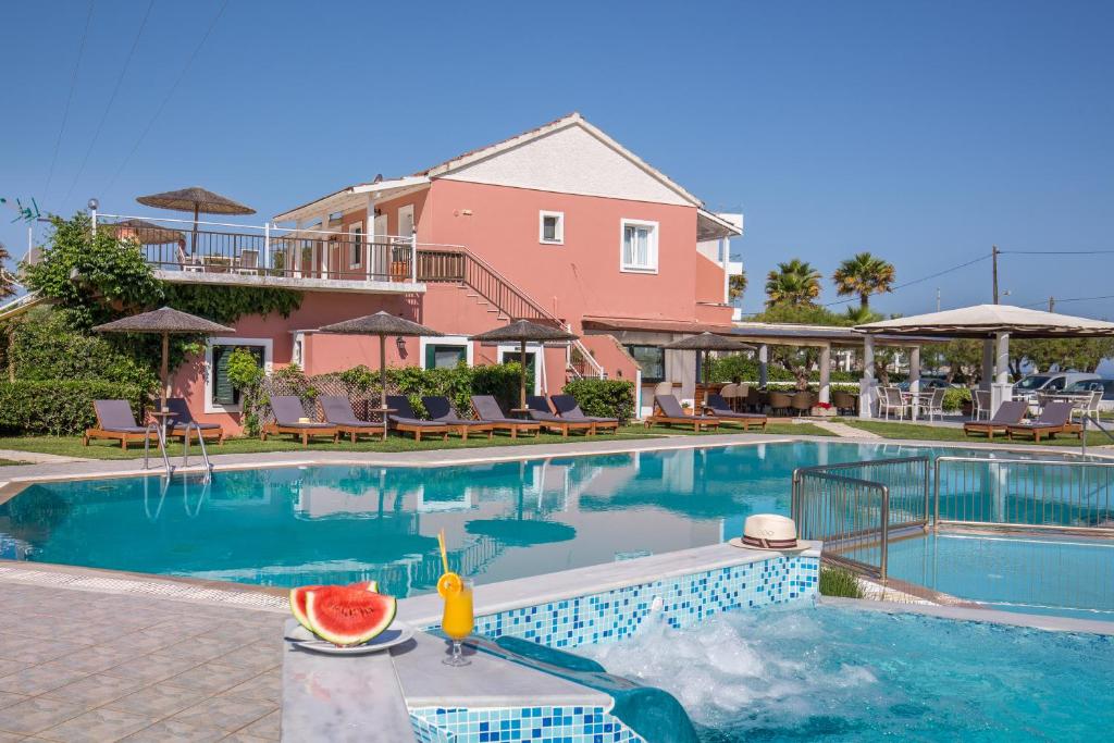 a swimming pool with a drink on a table next to a house at The Wave in Sidari