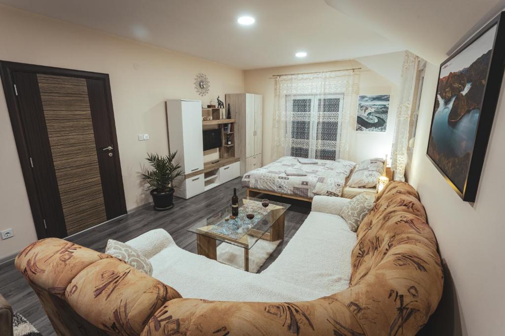 ein Wohnzimmer mit einem großen Sofa und einem Wohnzimmer in der Unterkunft Apartmani Stefan Zlatar in Nova Varoš
