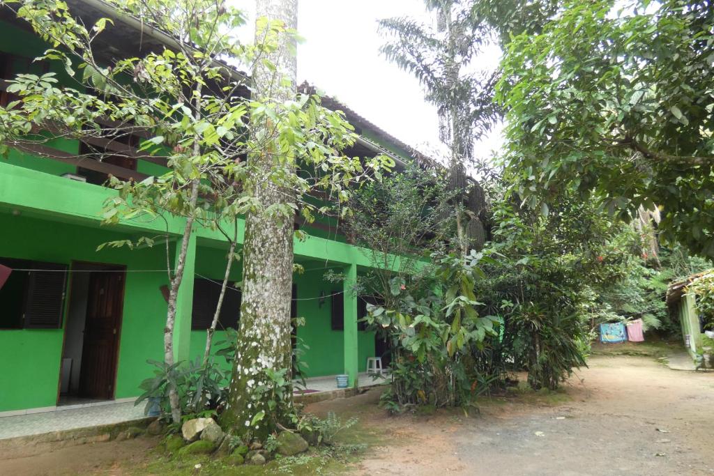 a green building with a tree in front of it at Pousada Jambo Trindade in Trindade