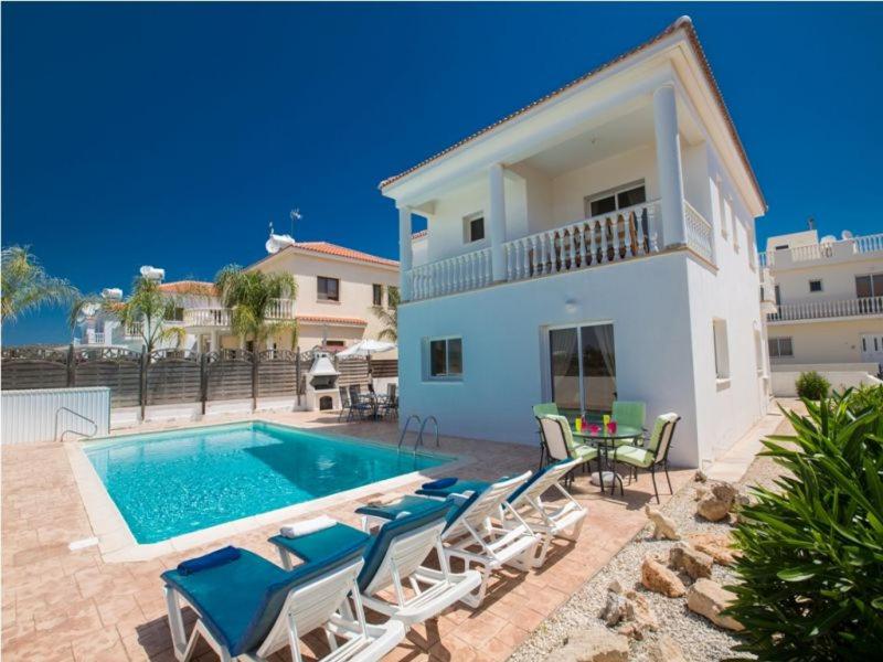 uma villa com piscina e cadeiras e uma casa em Carilisto Villas Big 4 Bedrooms in Center of Ayia Napa em Agia Napa