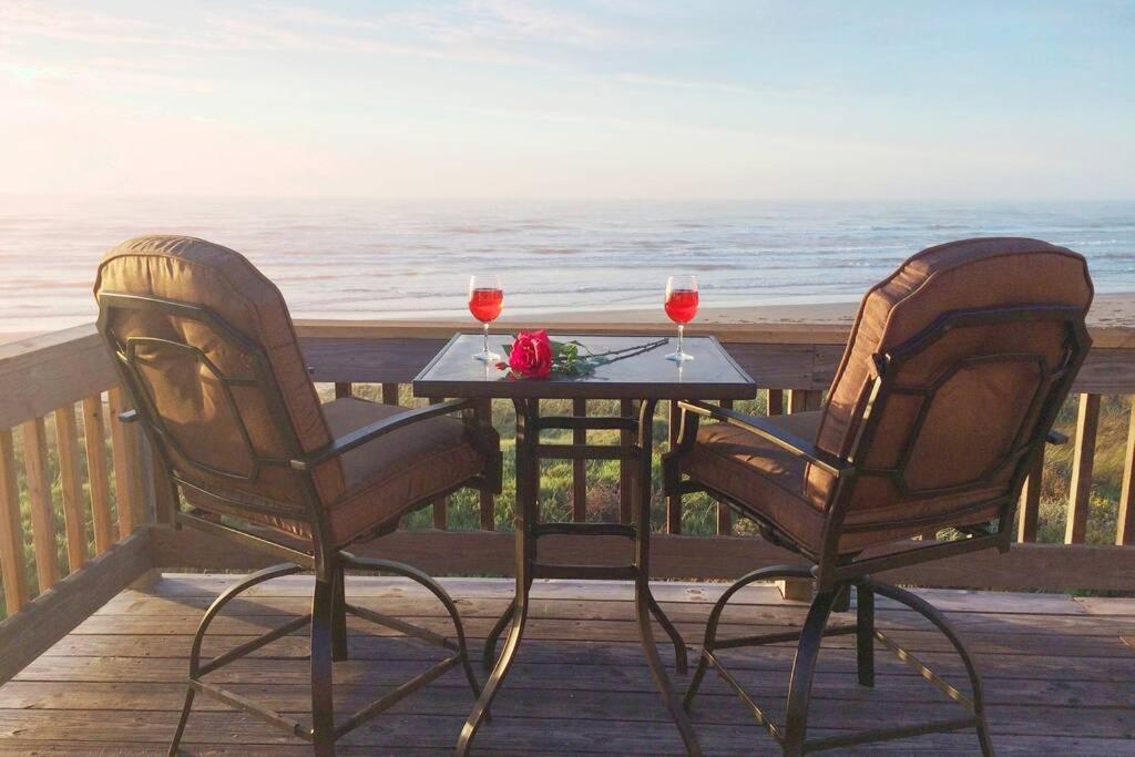 two chairs and a table with two glasses of wine at Beach Front on West Beach in Galveston