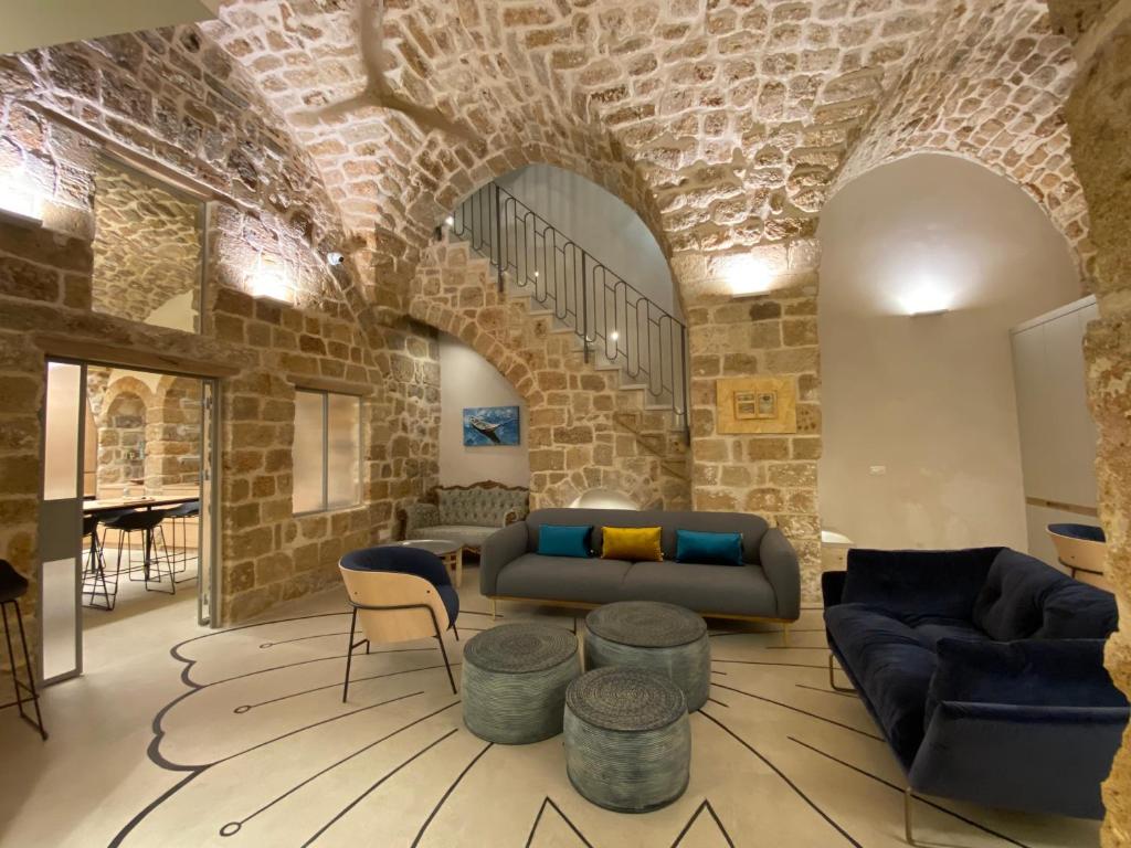 a living room with a couch and chairs and a brick wall at Beit Elfarasha in ‘Akko