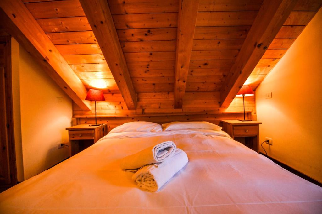 Łóżko w pokoju z drewnianymi sufitami i 2 lampami w obiekcie Residence Stalle Lunghe w mieście Prato Nevoso
