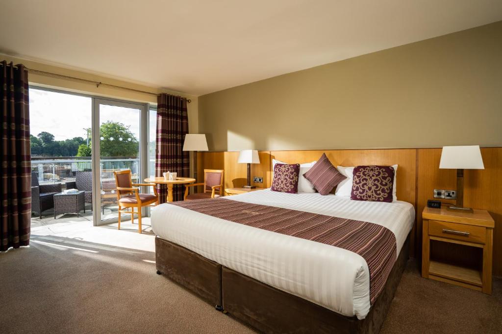 a hotel room with a large bed and a balcony at Belmore Court & Motel in Enniskillen