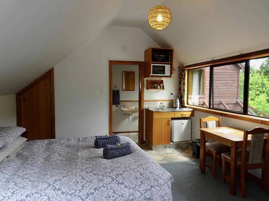 a bedroom with a bed and a desk and a kitchen at The Loft at Bealey in Arthur's Pass