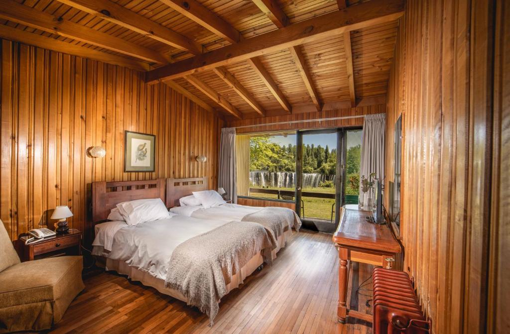 a bedroom with a bed and a large window at Hotel Salto Del Laja in Los Ángeles