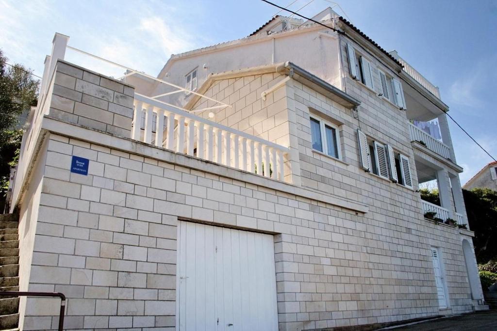 una casa de ladrillo blanco con una puerta de garaje blanca en Apartments Ivo - 20m from the sea, en Račišće
