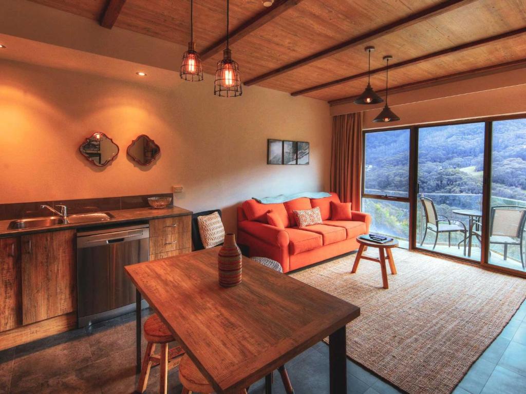a living room with a red couch and a table at Lantern 1 Bedroom Balcony Alpine Style in Thredbo