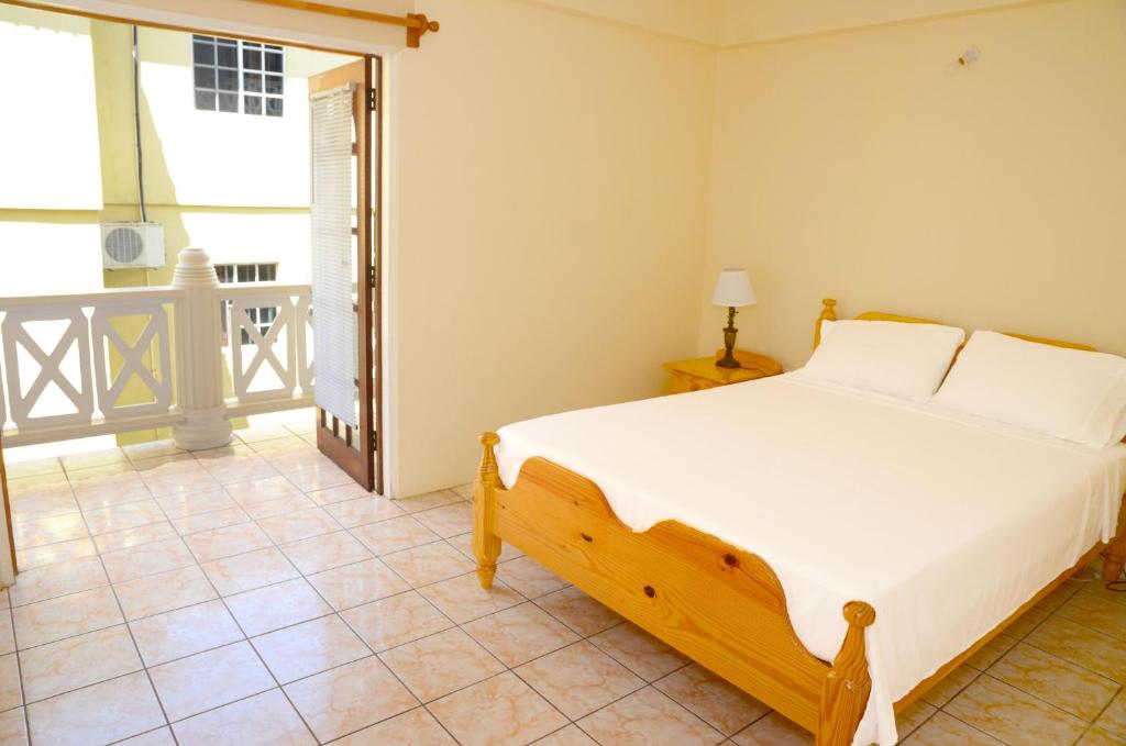 a bedroom with a bed and a balcony at Bascombe Apartments in Kingstown