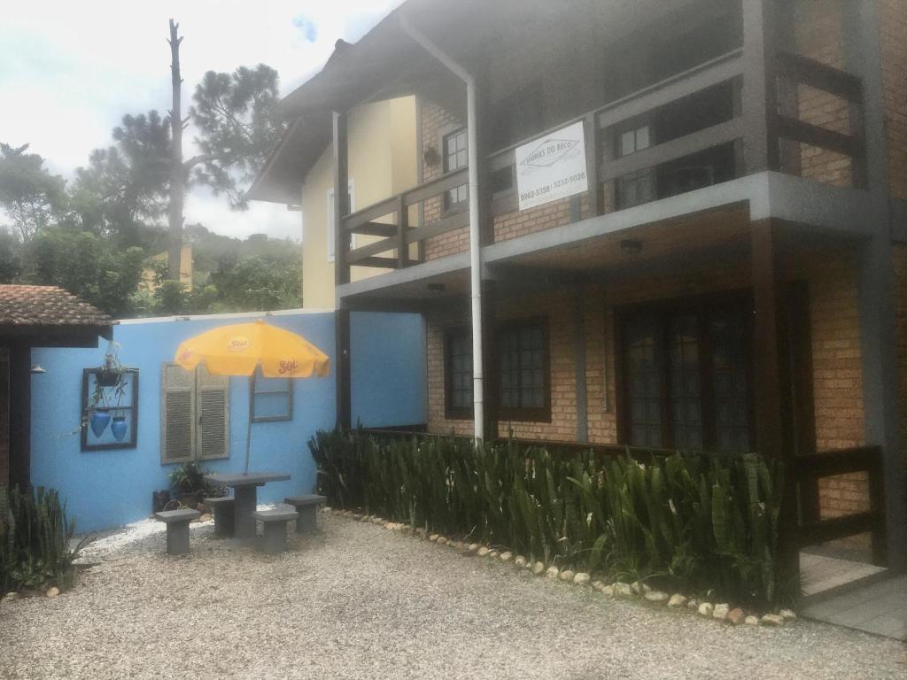 un edificio azul con sombrilla y banco en Chalé Dunas do Beco, en Florianópolis