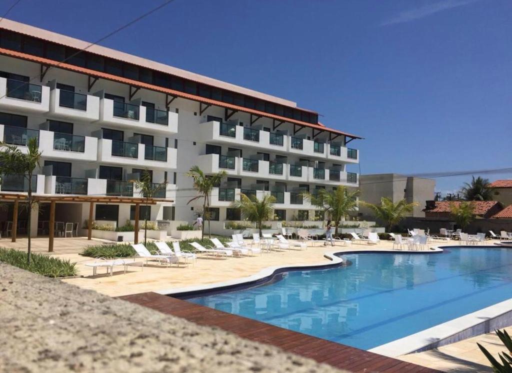 een hotel met een zwembad en ligstoelen bij Laguna Beach Flat -205 in Porto De Galinhas
