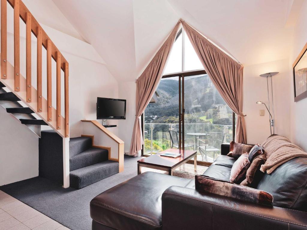 a living room with a couch and a large window at Lantern 1 Bedroom Loft with car space and Awesome View in Thredbo