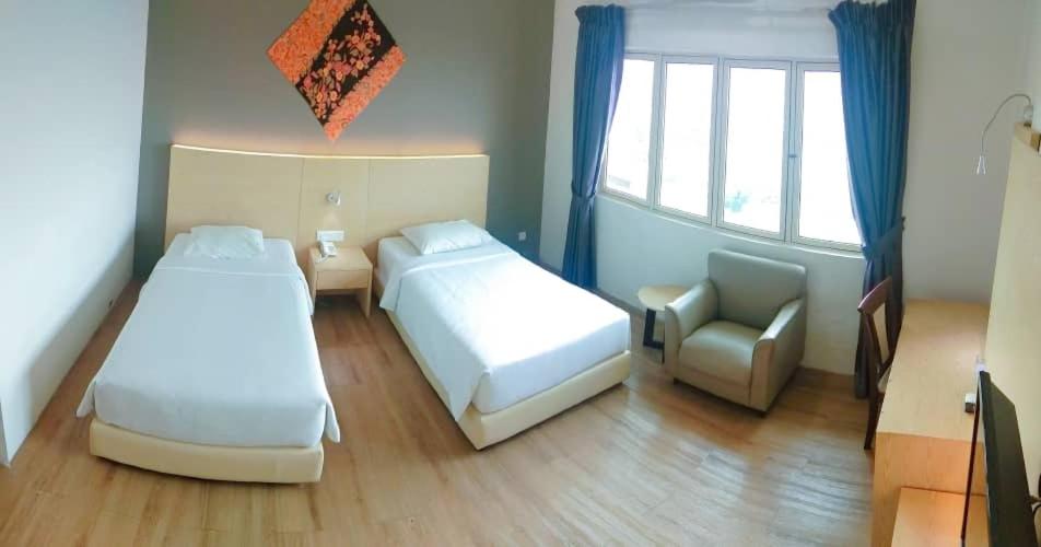 a bedroom with two beds and a chair and a window at Summit Signature Hotel Batu Pahat in Batu Pahat