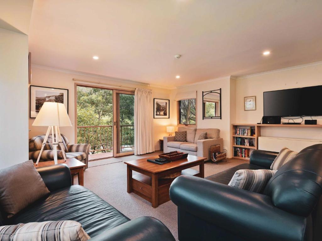 a living room with leather furniture and a tv at Lhotsky 2 Bedroom apartment with balcony mountain views and BBQ in Thredbo
