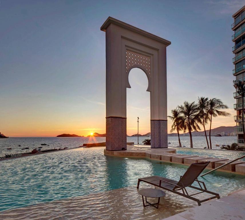 een stoel en een monument in het water voor de oceaan bij Apartamento Le Club Acapulco in Acapulco