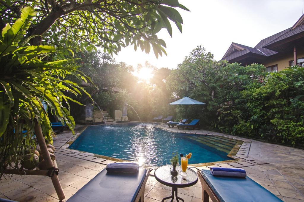 a swimming pool with a table and chairs next to it at Sri Phala Resort & Villa in Sanur
