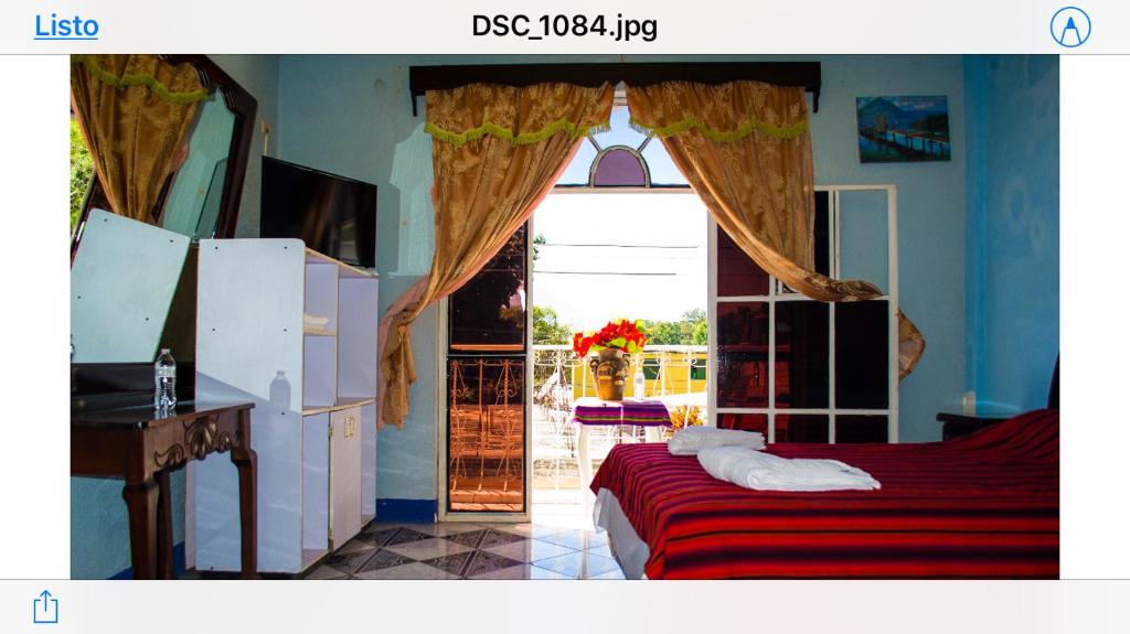 a bedroom with a bed and a large window at Hotel Amigo in Panajachel