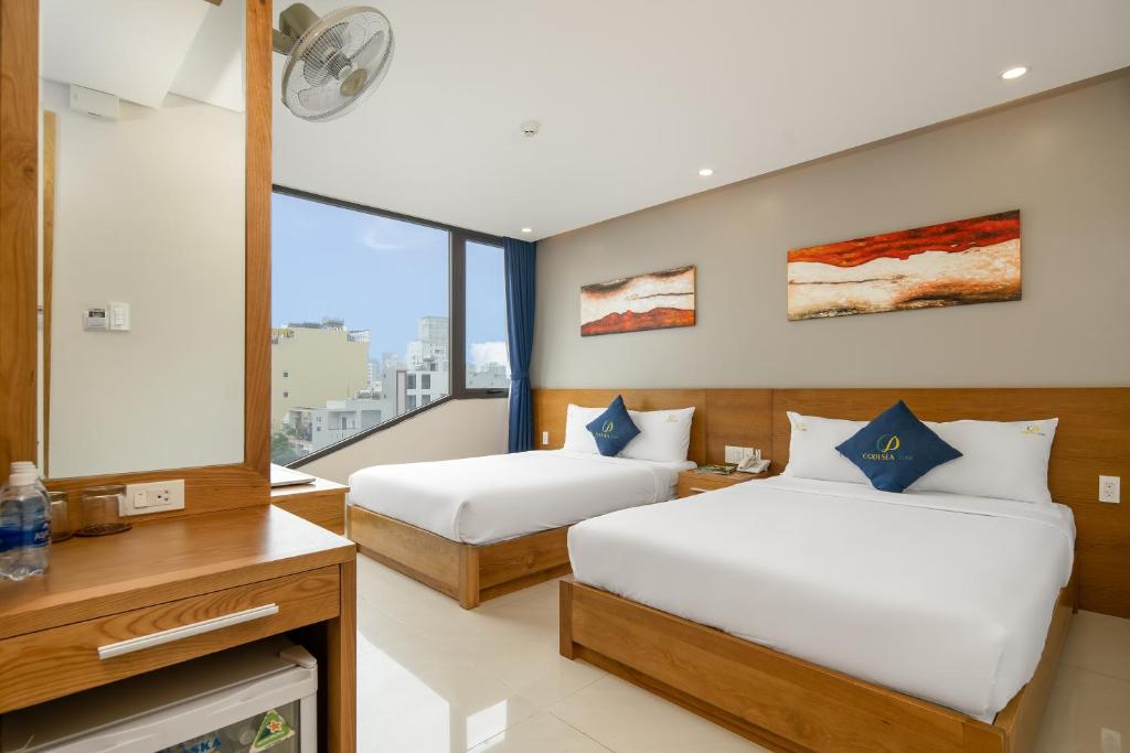 a bedroom with two beds and a large window at CODI SEA Hotel & Travel in Da Nang