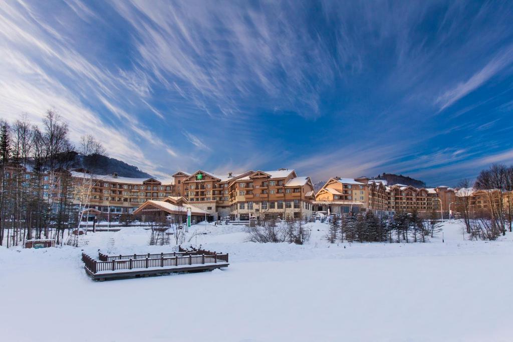 un complejo en invierno con nieve en el suelo en Wanda Jin Suites Changbaishan, en Fusong