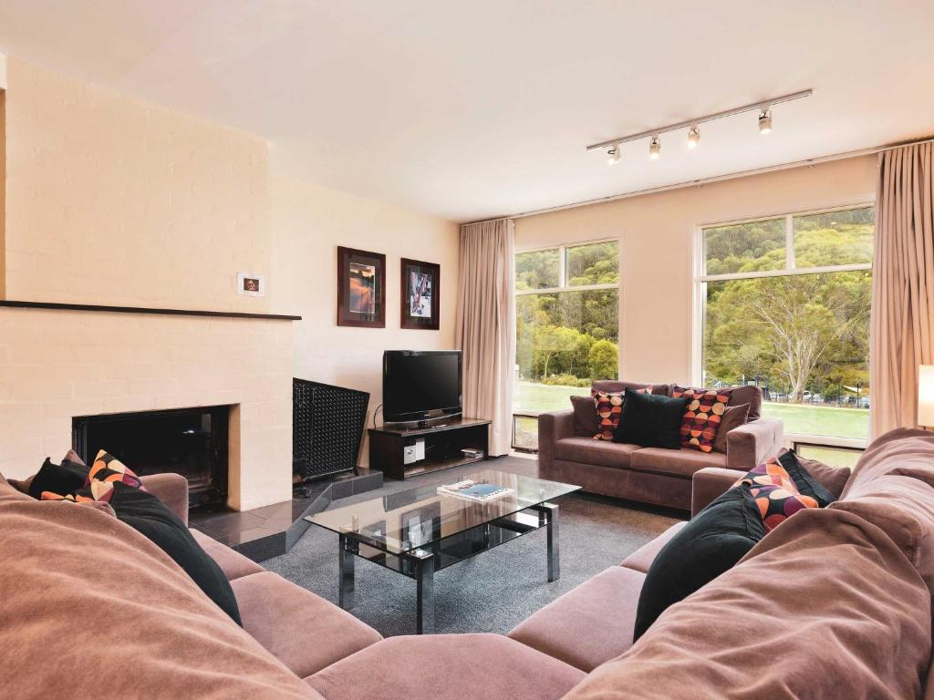 a living room with a couch and a fireplace at Village Green 2 Bedroom loft townhouse with views fireplace and garage parking in Thredbo