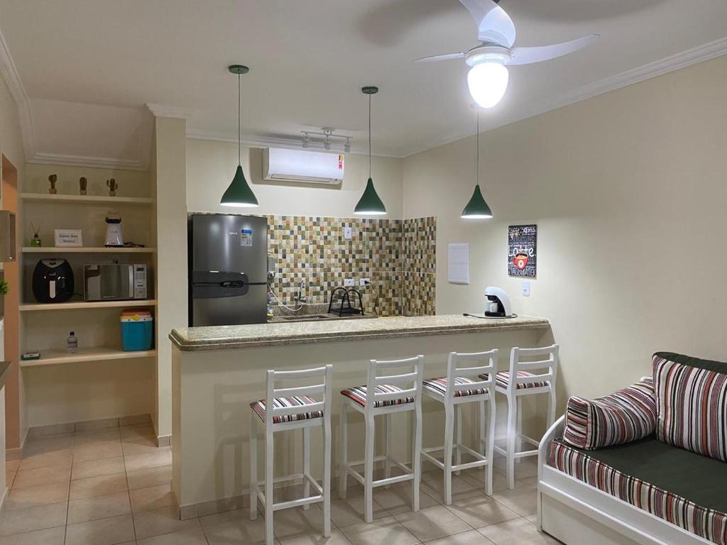 a kitchen with a bar with stools and a refrigerator at Flat Riviera de São Lourenço in Riviera de São Lourenço