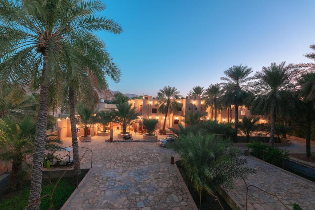 a resort courtyard with palm trees at night at نزل البستان Bustan lnn in Nizwa