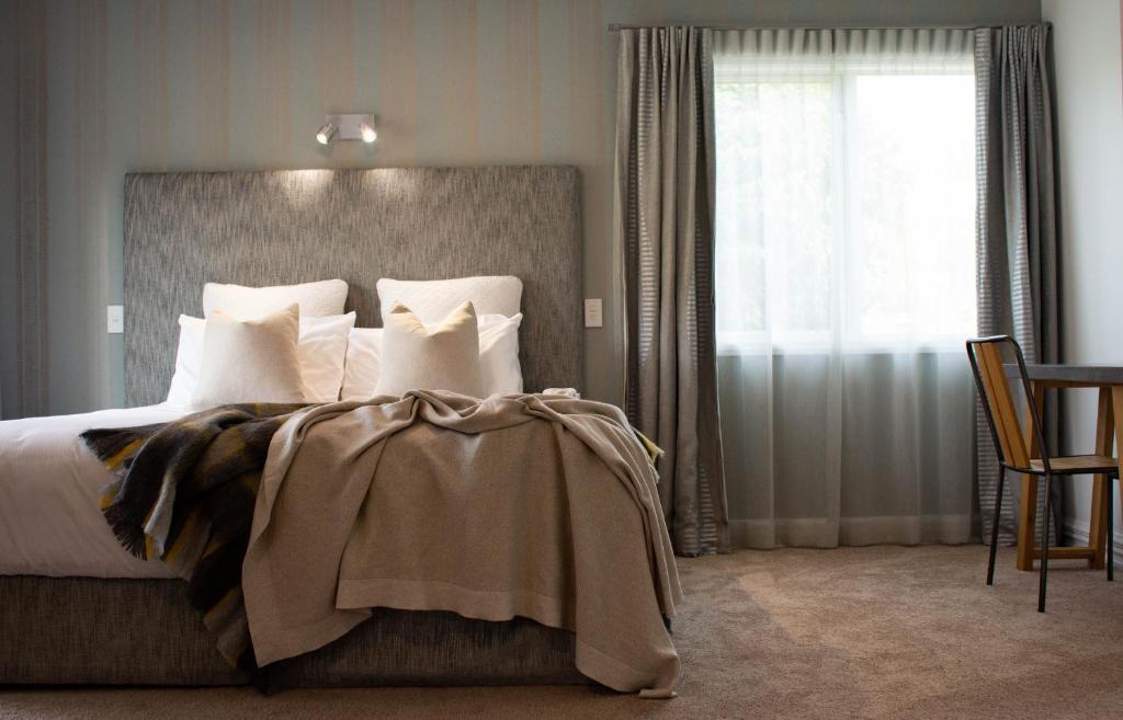 a bedroom with a bed with white pillows and a window at Queenstown Country Lodge in Queenstown