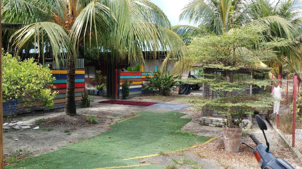 a garden with a fence and a yard with palm trees at Tony’s Guesthouse at Teluk Bahang in Batu Ferringhi