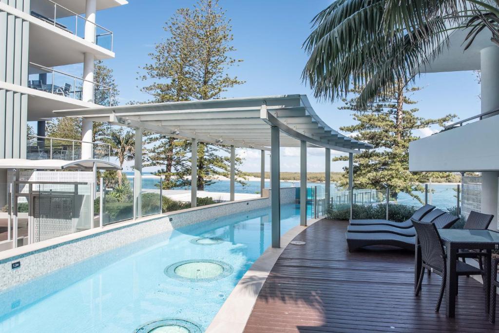 a swimming pool with a balcony overlooking the ocean at Rumba Beach Resort in Caloundra