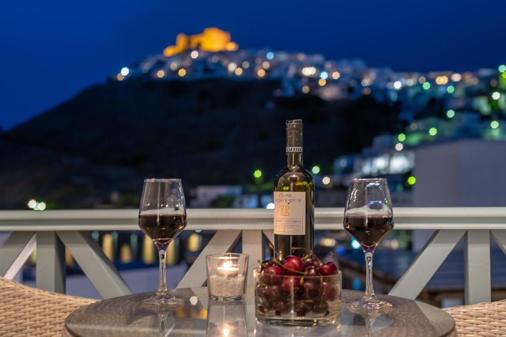 una bottiglia di vino seduta su un tavolo con due bicchieri di Niriides Luxury Studios a Astypalaia Town