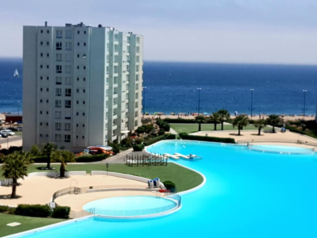 a large swimming pool in front of a large building at Departamento Lago & Mar in Papudo