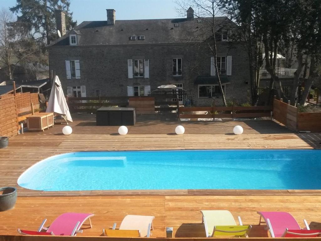 a swimming pool with chairs and a house in the background at Domaine naturiste libertin et épicurien B&B spa in Condé-sur-Noireau