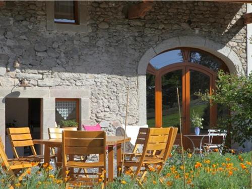 a wooden table and chairs in front of a stone building at Chambres d'hôtes-Les Chambres de Mado in Margencel