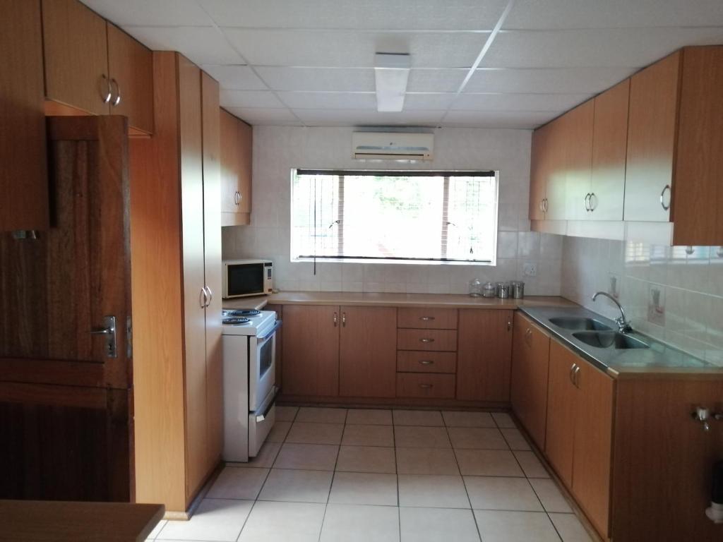 a kitchen with wooden cabinets and a sink and a window at BLS (Baie Lekker Slaap) in Bloemfontein
