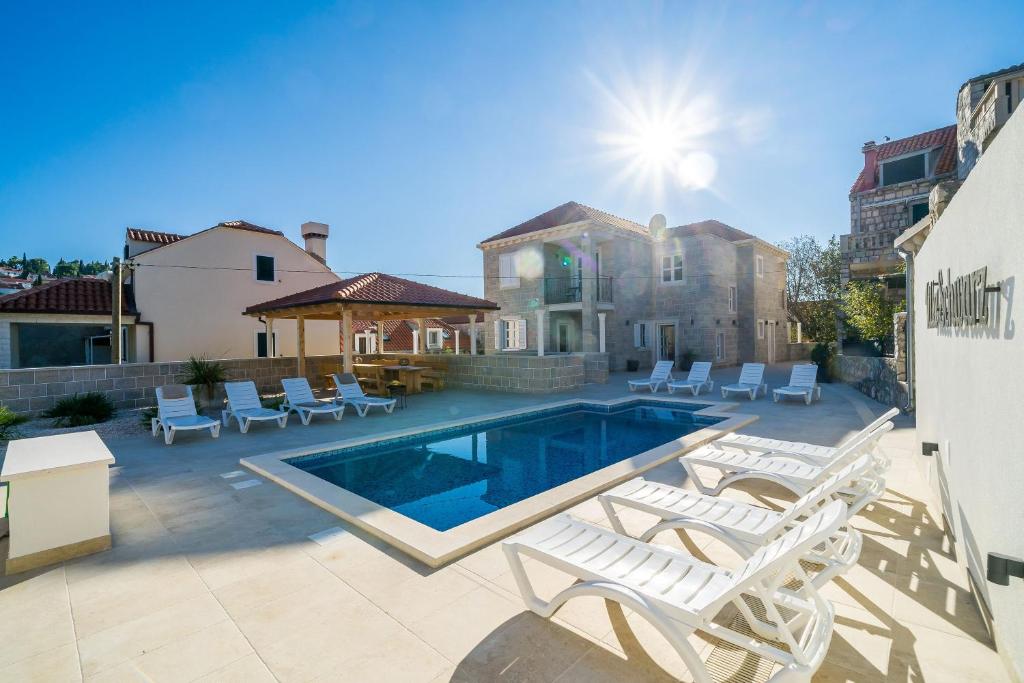 uma casa com uma piscina e duas espreguiçadeiras em Residence & Pool Villa Schwarz Suites em Cavtat