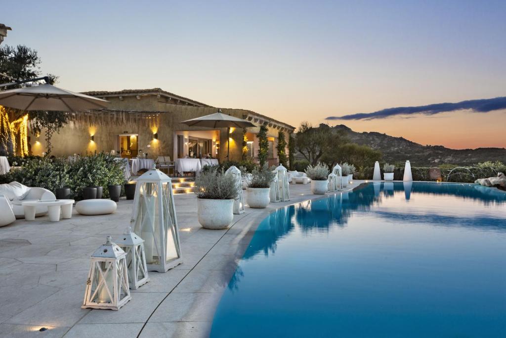 a pool at a resort with chairs and umbrellas at Hotel Li Finistreddi in Cannigione