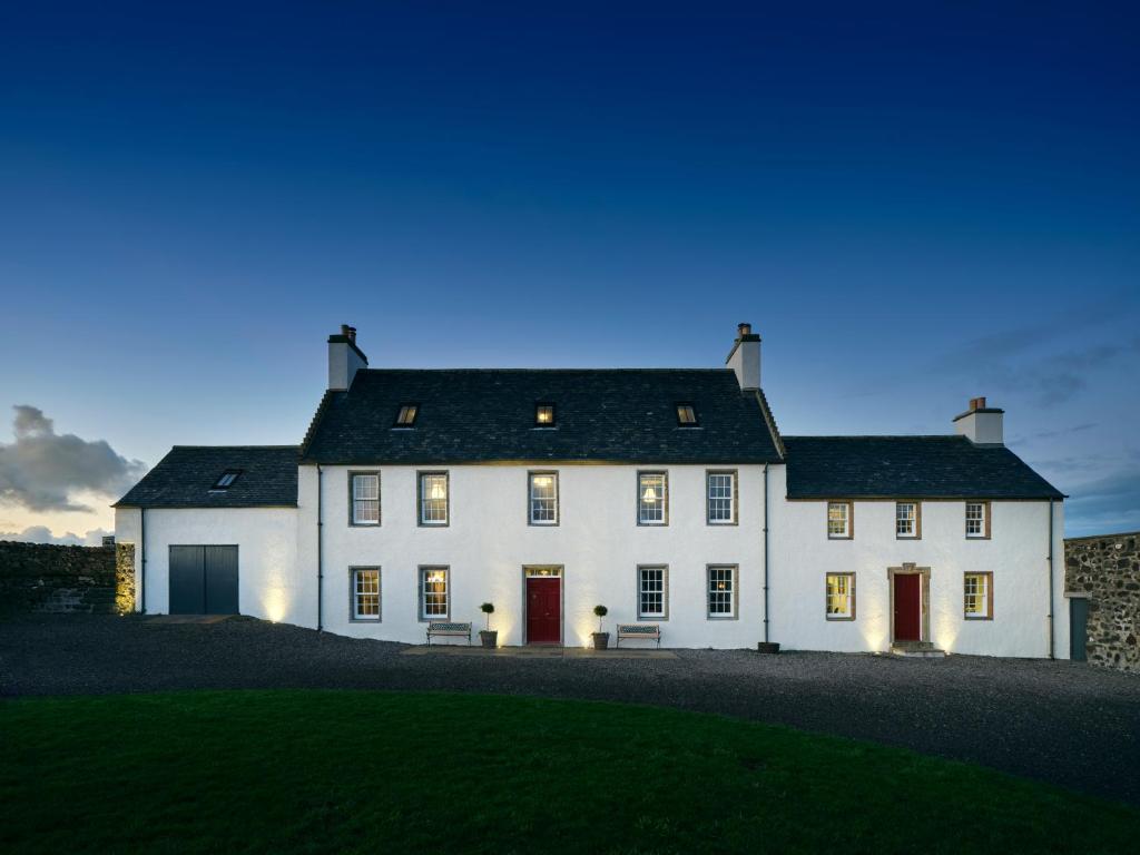 a large white house with two red doors at Monkstadt 1745 Luxury Lodge in Portree