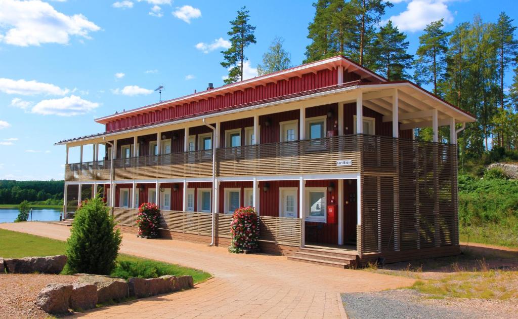 a large wooden building with a red roof at Woikoski Feeling - WHD Gård in Nurmaa