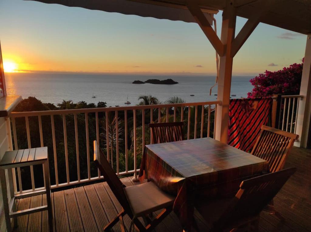 una mesa y sillas en un porche con vistas al océano en Villa Azur B, en Bouillante