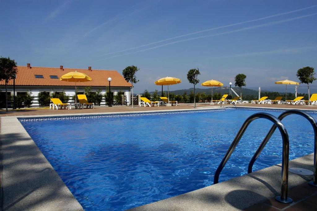 una piscina con sombrillas amarillas, mesas y sillas en Apartamentos Casa Ameiros, en San Vicente de O Grove