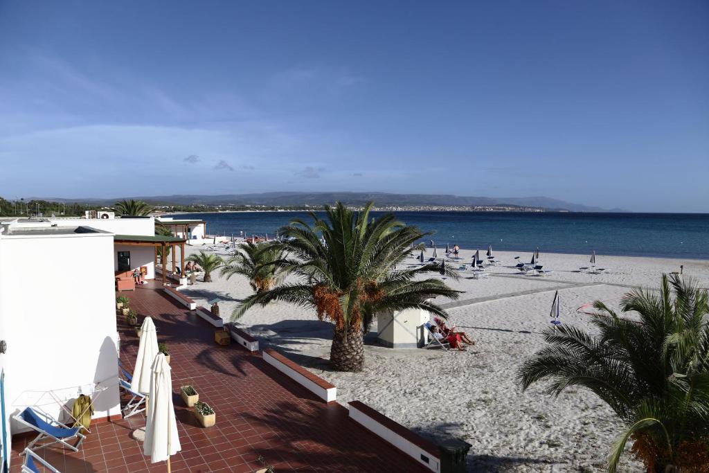 una spiaggia con palme e persone sulla spiaggia di Vel Marì - Rooms on the Beach ad Alghero