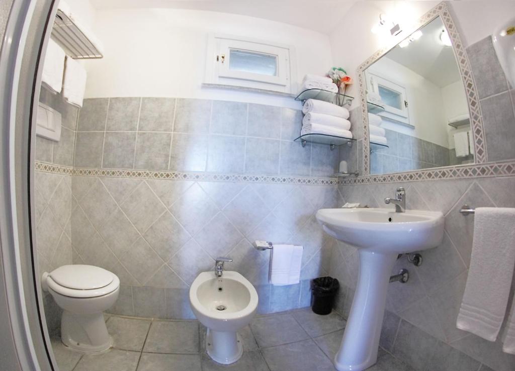 een badkamer met een wastafel, een toilet en een spiegel bij Vel Marì - Rooms on the Beach in Alghero