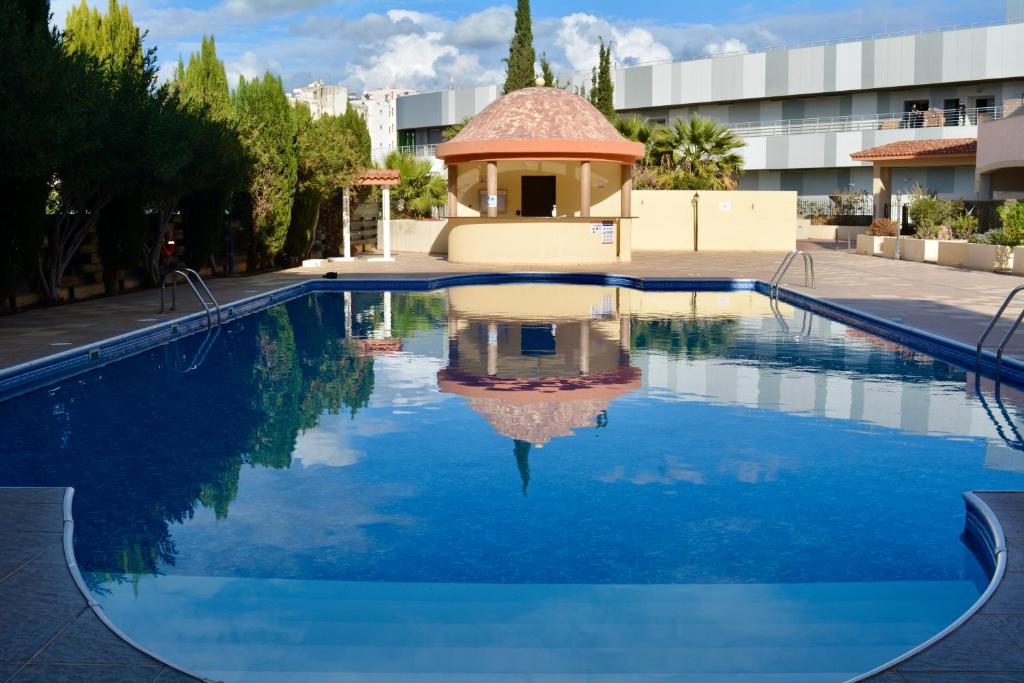 a swimming pool with a gazebo next to a building at Queens Gardens - Kato Paphos - next to Kings Ave Mall --- by Yiota in Paphos