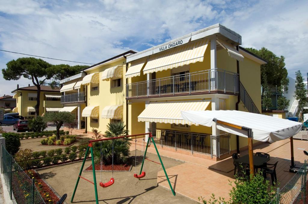 um edifício amarelo com um parque infantil em frente em Villa Ongaro em Lido di Jesolo