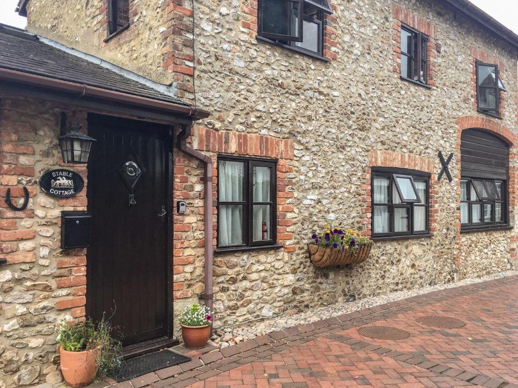 a stone building with windows and a door and flowers at Stable Cottage in Colyton