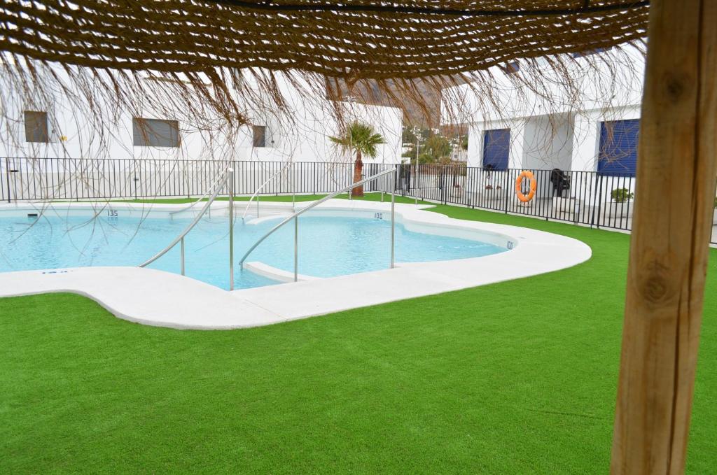 una piscina en un patio con césped verde en Apartamentos Cala San Pedro, en Las Negras